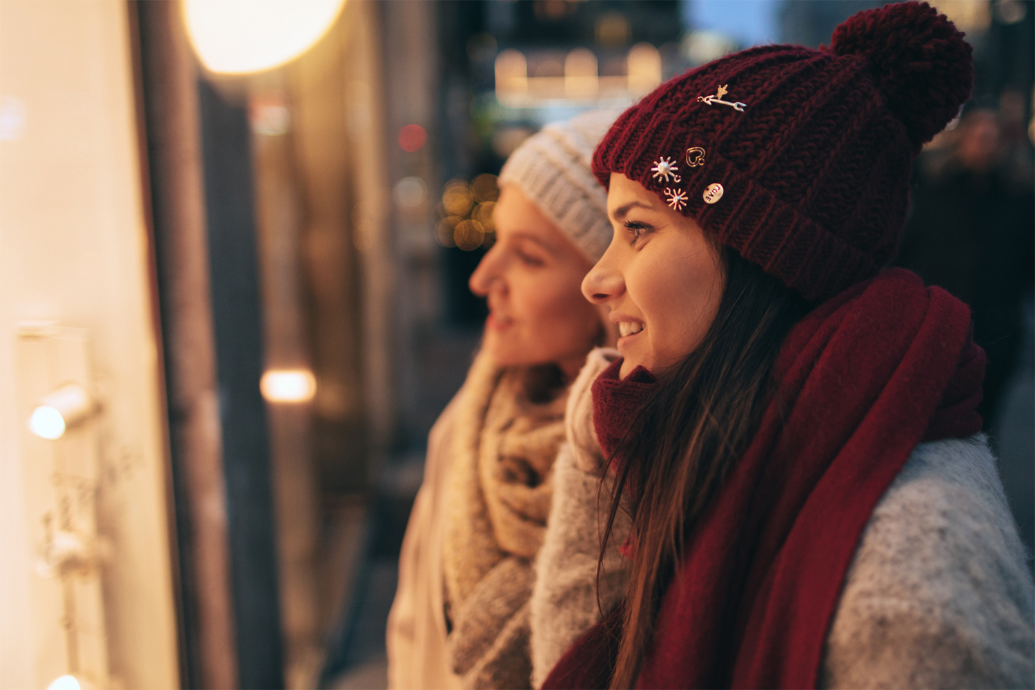 two women looking through store window in winter